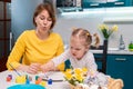 Easter celebration. Mother and her toddler daughter painting eggs. Little girl having fun and paints on plate Royalty Free Stock Photo