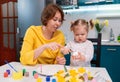 Easter celebration and traditions. A smiling mother and her little daughter are painting eggs. Educator teaching a Royalty Free Stock Photo