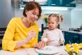 Easter celebration and traditions. Smiling mother and her toddler daughter painting eggs. Young woman teaching a little Royalty Free Stock Photo