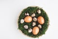 Easter.Chicken eggs and quail eggs lie in a basket with moss on a white background, top view. Spring, April