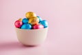 Easter chocolate eggs wrapped in aluminium foil in bowl on pink background Royalty Free Stock Photo