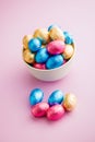 Easter chocolate eggs wrapped in aluminium foil in bowl on pink background Royalty Free Stock Photo