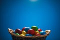 Easter color eggs in festive gift basket, blue background