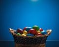 Easter color eggs in festive gift basket, blue background