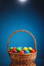 Easter color eggs in festive gift basket, blue background