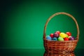 Easter color eggs in festive gift basket, green background with copy-space