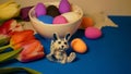 Easter with colored chicken eggs in a white plate with a porcelain rabbit figurine, red tulip flowers on a retro lace napkin on a Royalty Free Stock Photo