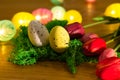Easter colored eggs on green grass around tulips and wooden board Happy Easter