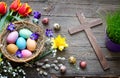 Easter colorful eggs in the nest with flowers on vintage wooden boards  and cross Royalty Free Stock Photo