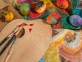 Easter colorful eggs with two painter's brushes,a wooden palette and a hand painted cloth. Royalty Free Stock Photo