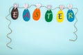 Easter multicolored paper shaped eggs with the inscription EASTER hanging on a rope on clothespins Royalty Free Stock Photo