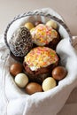 Easter concept composition with beautifully decorated Easter cake, dyed eggs, chocolate egg in a basket on linen fabric