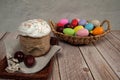 A basket of colorful eggs and a glazed Easter cake decorated with sugar sprinkles stand on a wooden table Royalty Free Stock Photo
