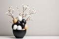 Easter composition with a black bowl full of black, white and brown eggs and white flowers. Copy space. Poster or banner