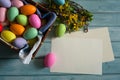 Blank paper, Forsythia branches with yellow flowers and colorful Easter eggs on a light blue wooden background. Royalty Free Stock Photo