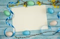 A blank sheet of paper, branches of forsythia with yellow flowers, ribbons and Easter eggs on a light blue wooden background. Royalty Free Stock Photo