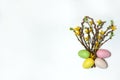 The bouquet consists of branches of forsythia with yellow flowers, willow with fluffy buds and colorful eggs on a white background
