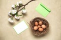 Easter composition. Brown eggs, cherry blossom branch artificial and mockup blank greeting card. Concrete background. Top view,