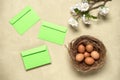 Easter composition. Brown eggs in the nest, sakura blossom branch artificial and green envelope. Concrete beige background. Top