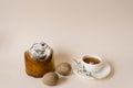 An Easter composition with a cake and eggs and a cup of tea with a sprig of a flowering apple tree on a light background. Easter