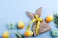 Easter composition with craft paper package in the shape of.bunny, colorful easter eggs, and flowers. Flat lay, copy space Royalty Free Stock Photo