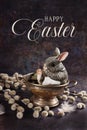 Easter composition with a cute bunny figurine and catkin twigs on grunge background with greeting text