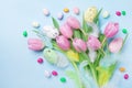 Easter composition with eggs, spring flowers, feathers and colorful candy on blue table top view.