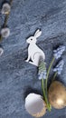 Easter composition with flowers, white wooden rabbit and eggs flat lay, top view on cement background. Royalty Free Stock Photo