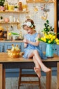 Easter composition. A girl in the kitchen with tulips at the table with ducklings sitting in a basket
