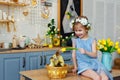 Easter composition. A girl in the kitchen with tulips at the table with ducklings sitting in a basket