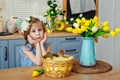 Easter composition. A girl in the kitchen with tulips at the table with ducklings sitting in a basket