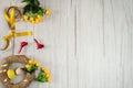 Blank for a wreath, colorful eggs, cute red birds, yellow flowers, ribbons and a bow on a wooden background.