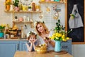 Easter composition. Mother and daughter with flower wreaths on their heads at the kitchen table and play with ducklings. A woman