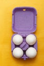 Easter composition. Set of Four white eggs in purple box on yellow background Royalty Free Stock Photo