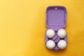 Easter composition. Set of Four white eggs in purple box on yellow background Royalty Free Stock Photo