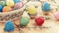 Easter composition - several colored eggs in a basket and on a light wooden table with willow twigs