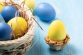 Easter composition - several colored eggs in a basket and stand on a blue wooden table