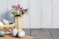 Easter composition - several eggs painted with natural dyes and wildflowers in a vase