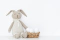 Easter composition with a soft rabbit toy and white eggs in a basket on a shelf in the room