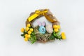 A wreath with a cute handmade Easter Bunny and an egg in the nest, yellow spring flowers on a white background. Royalty Free Stock Photo