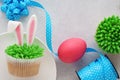 Easter concept with bunny ears cupcakes, blue ribbon, pink egg