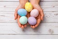 Easter concept. closeup beautiful woman hands holding hand-painted easter eggs in tender pastel colors over wooden table Royalty Free Stock Photo
