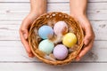 Easter concept. closeup beautiful woman hands holding a wicker basket with hand-painted easter eggs in tender pastel colors and Royalty Free Stock Photo