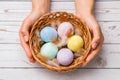 Easter concept. closeup beautiful woman hands holding a wicker basket with hand-painted easter eggs in tender pastel colors and Royalty Free Stock Photo