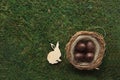 Easter concept - nest with chocolate eggs and a rabbit on green background flat lay Royalty Free Stock Photo