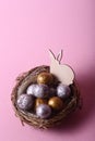 Easter concept - rabbit in a nest with chocolate eggs against pink background Royalty Free Stock Photo