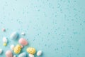 Top view photo of colorful easter eggs and scattered sprinkles on isolated light blue background with copyspace Royalty Free Stock Photo