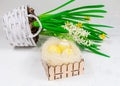 Easter concept. Yellow Easter eggs in a basket next to a bouquet of daffodils on a white concrete table. Place for an