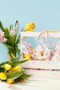 Easter cookies in personal package bag with pastel colored icing in wooden box and spring flowers on blue background. Happy easter Royalty Free Stock Photo