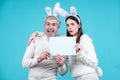 Easter couple having fun with rabbit ears. Easter egg hunting. Bunny couple hold board paper for text. Family Royalty Free Stock Photo